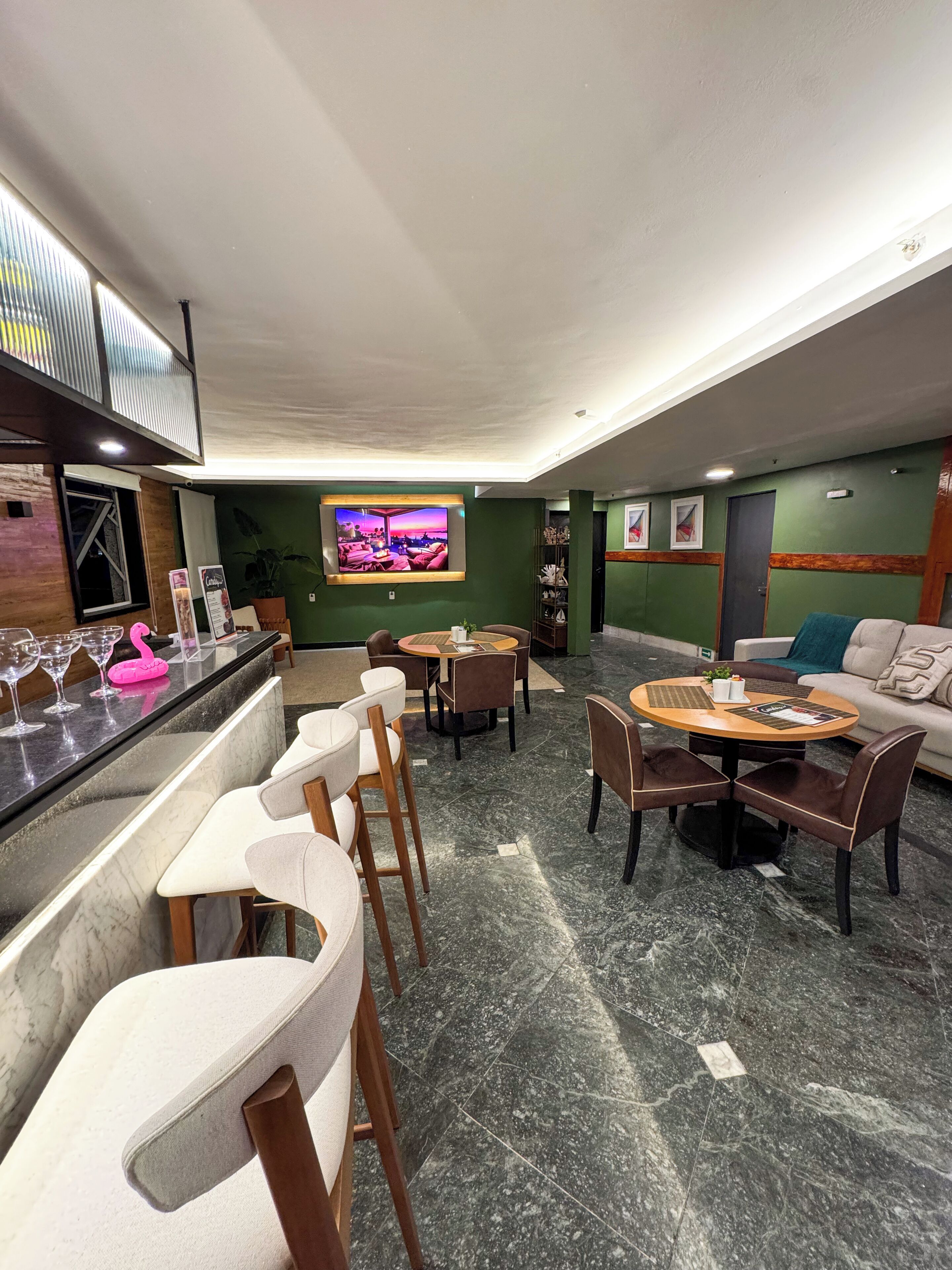 A modern lounge area with a bar, seating arrangements, and a television screen.