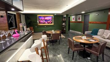 A modern lounge area with a bar, seating arrangements, and a television screen.