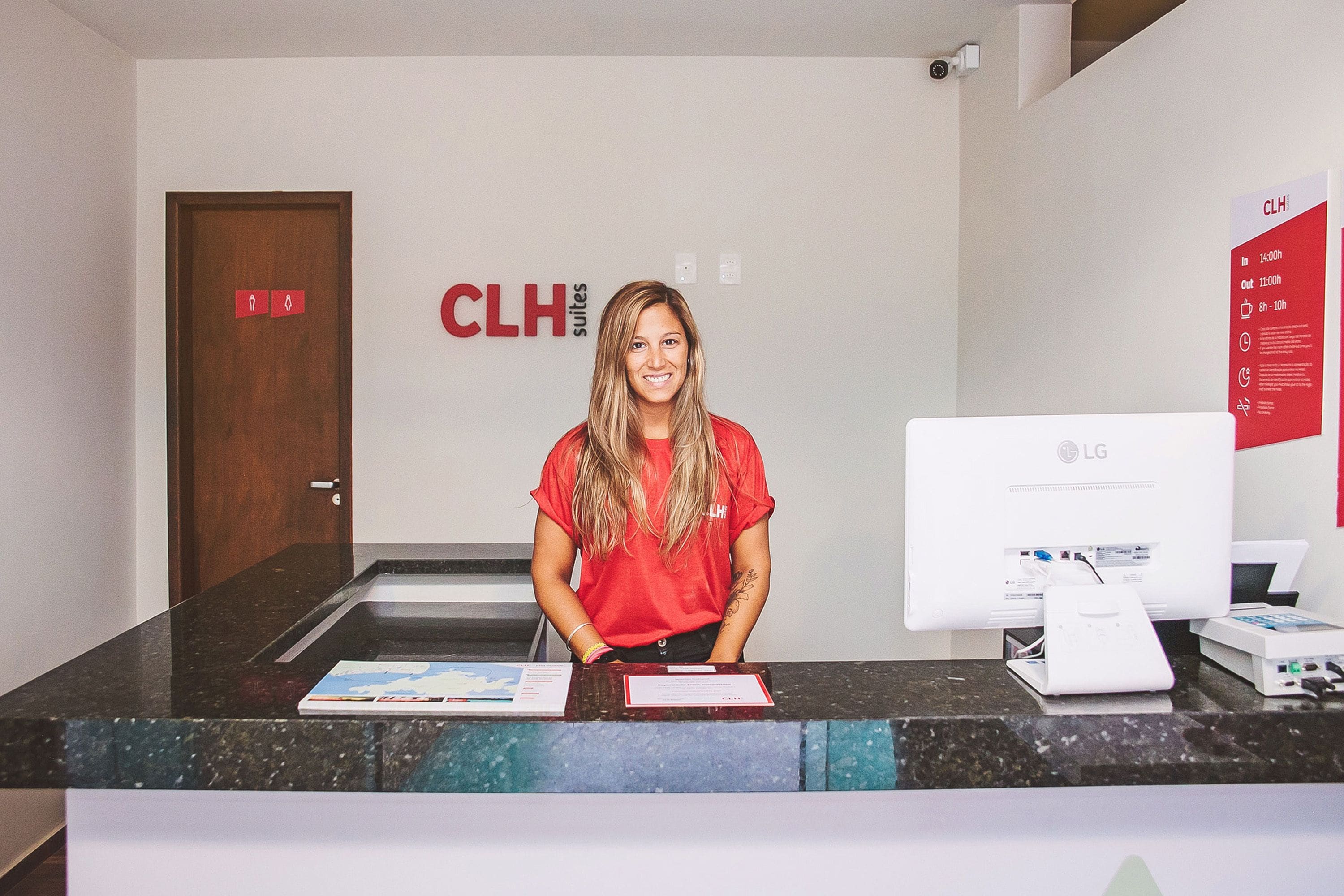 A reception desk with a computer monitor, a printer, and a sign indicating room availability.