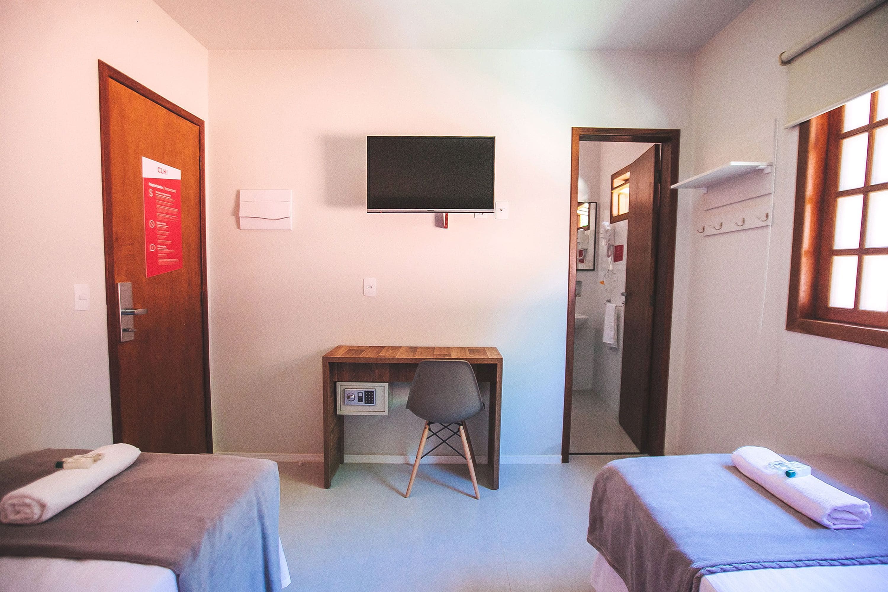 Habitación de hotel con dos camas, un escritorio, una silla, un televisor y un espejo.