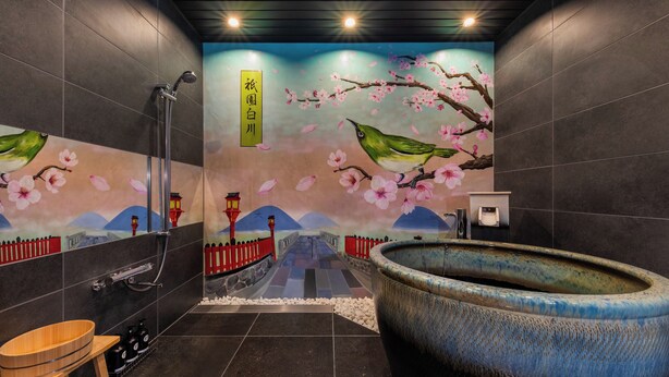 A modern bathroom with a large ceramic sink, a shower with a handheld showerhead, and a decorative wall mural depicting cherry blossoms and a traditional bridge. - Shiki Homes SHINJIN (Kyoto)