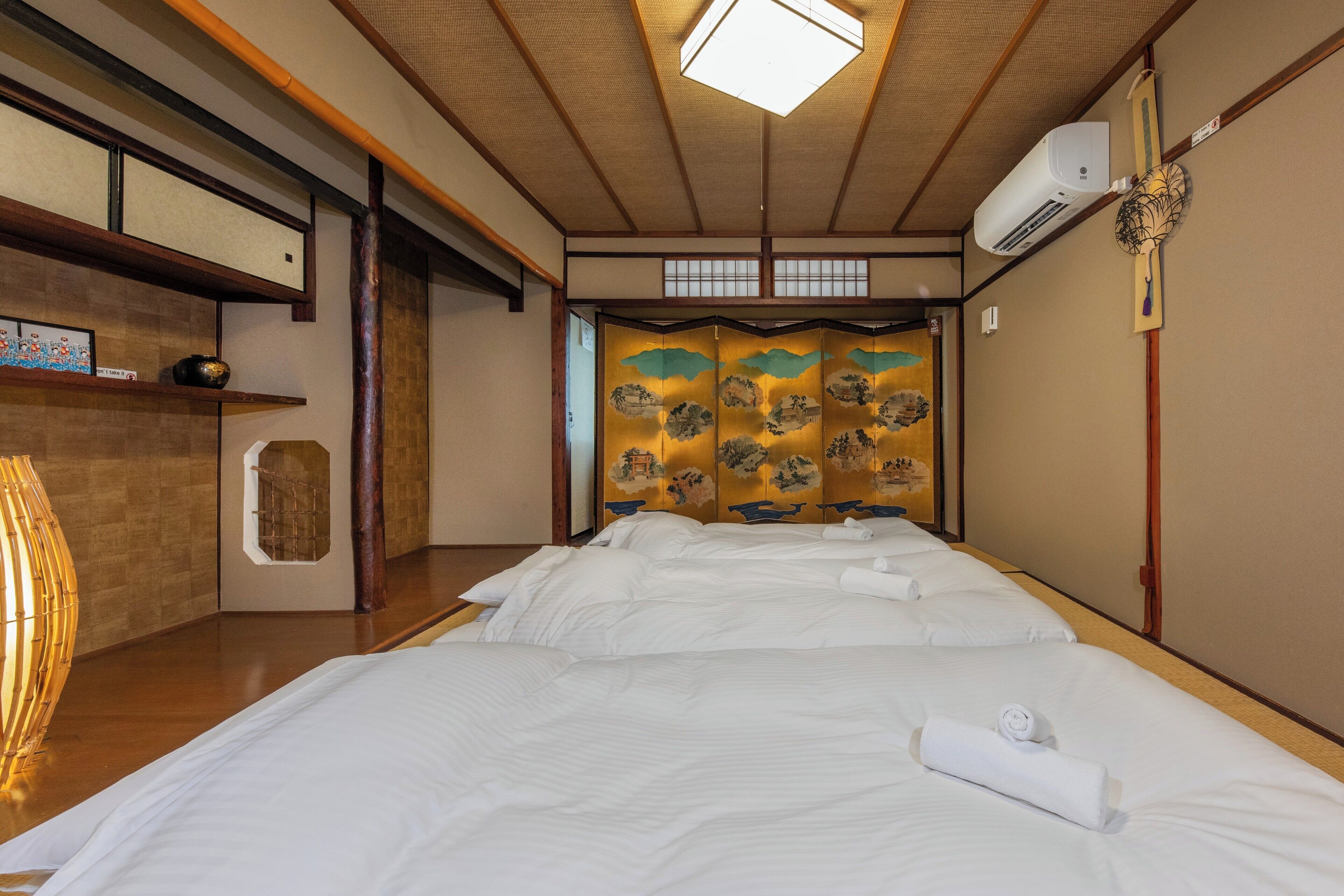 A traditional Japanese-style room with tatami flooring, a shoji screen, and a futon bed arrangement.