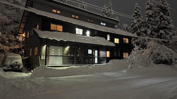 A two-story building with a covered entrance and a car parked in front.
