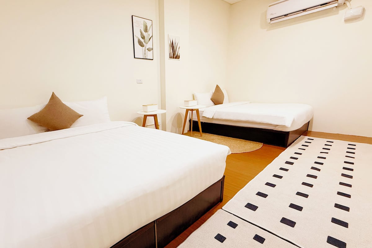 Une chambre d’hôtel avec deux lits, une petite table et un climatiseur fixé au mur.