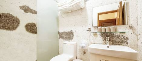 A bathroom with a toilet, sink, and a glass shelf with toiletries.