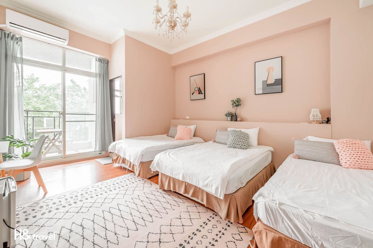 Une chambre d’hôtel avec trois lits, une grande fenêtre, un lustre et une vue sur l’extérieur.