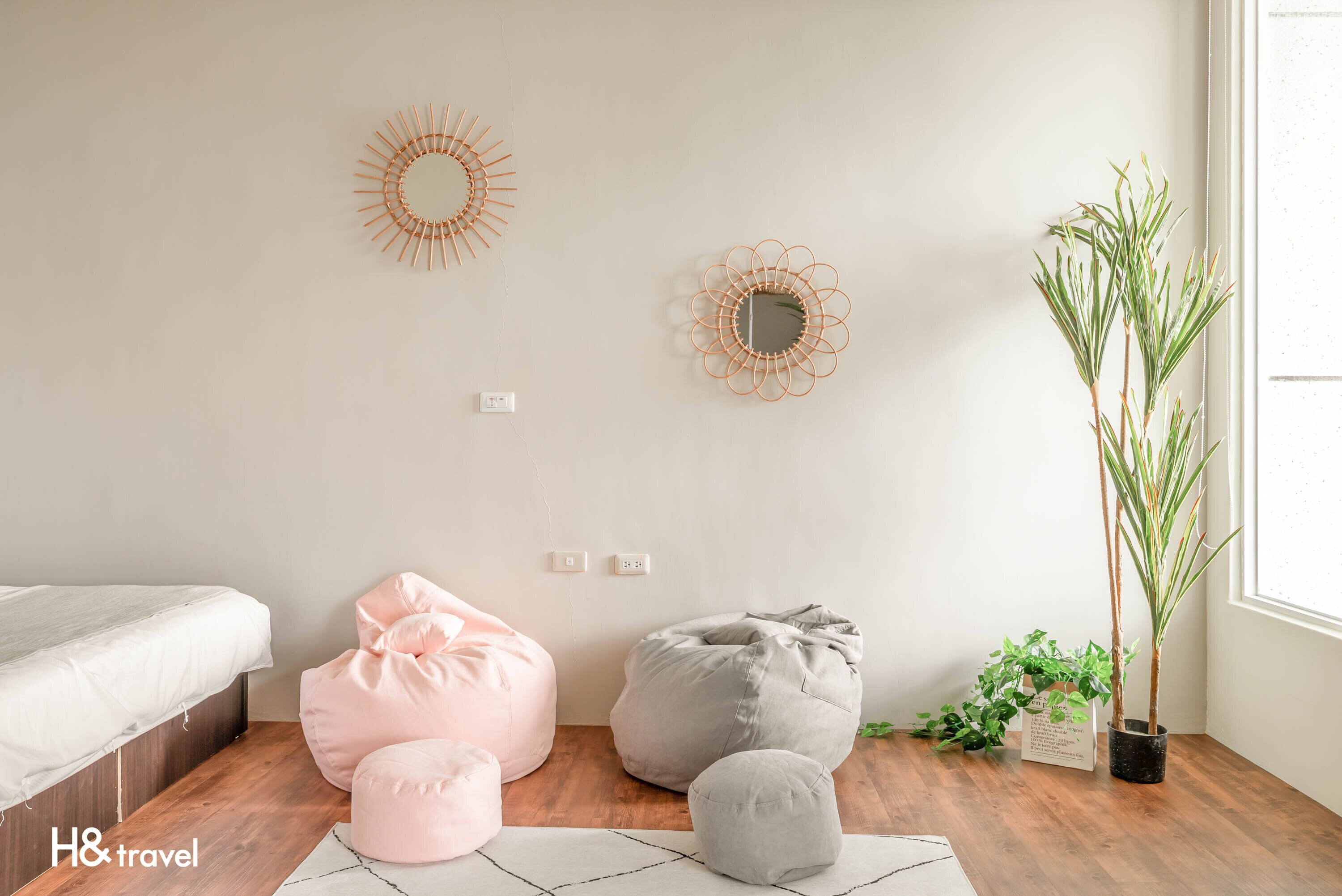A bedroom with a bed, two bean bags, a potted plant, and wall decor.