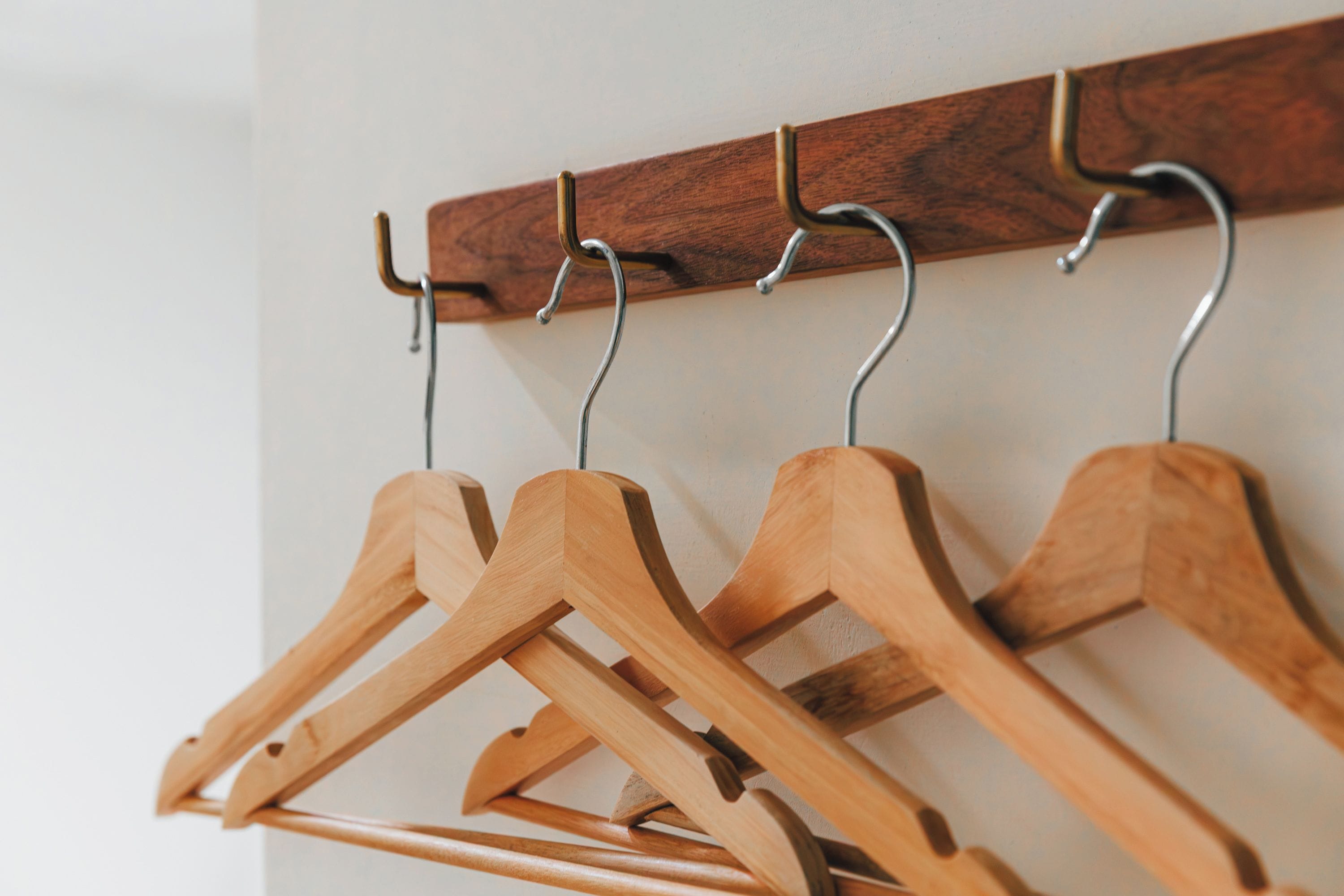 A wooden coat rack with multiple hangers against a wall.