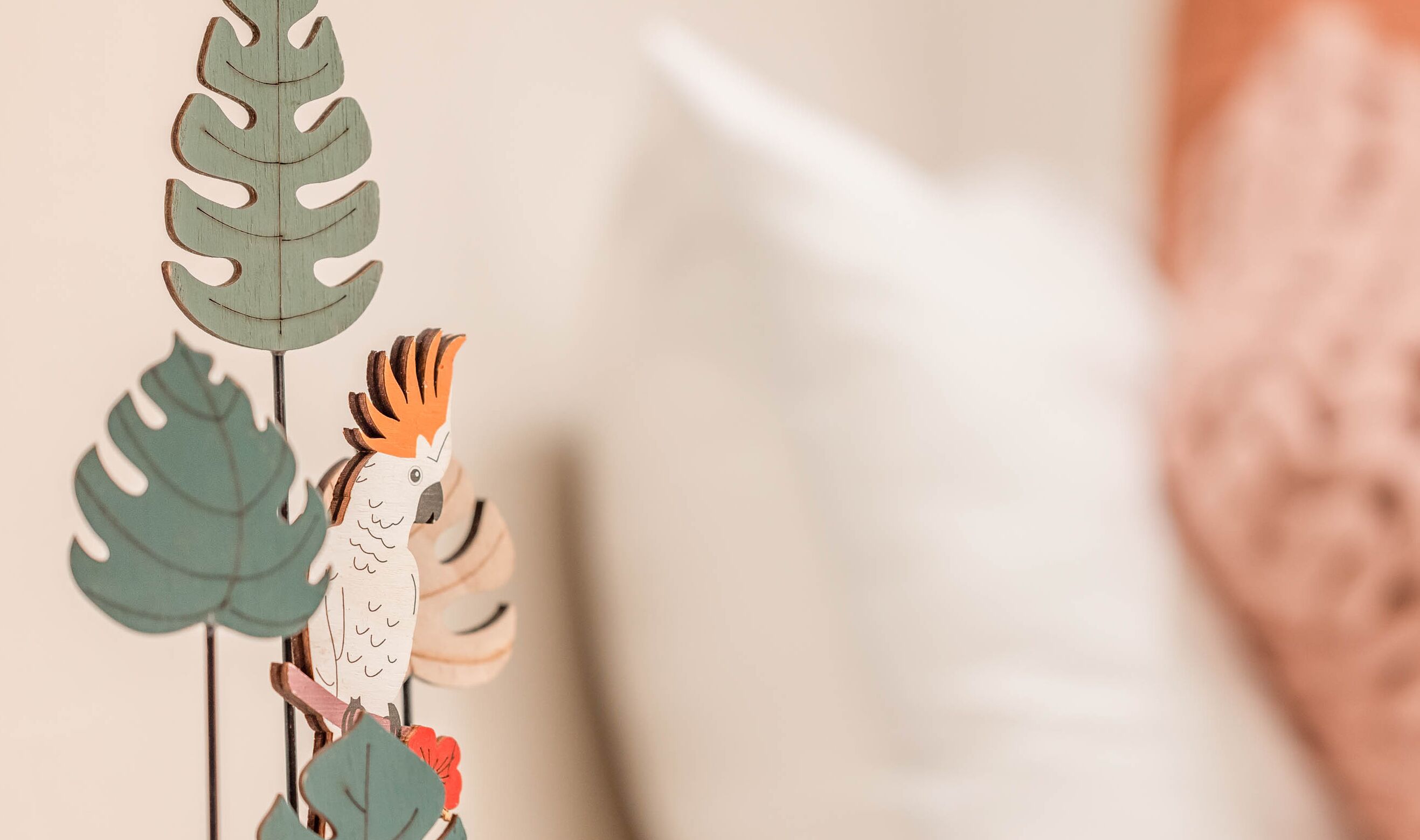 A decorative wooden bird with a red crest, surrounded by green leaves.