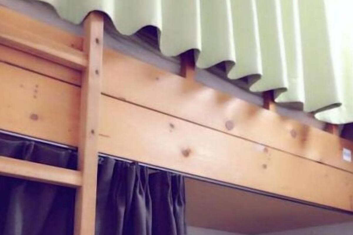 Ein Etagenbett mit Holzgestell und grüner Vorhang.