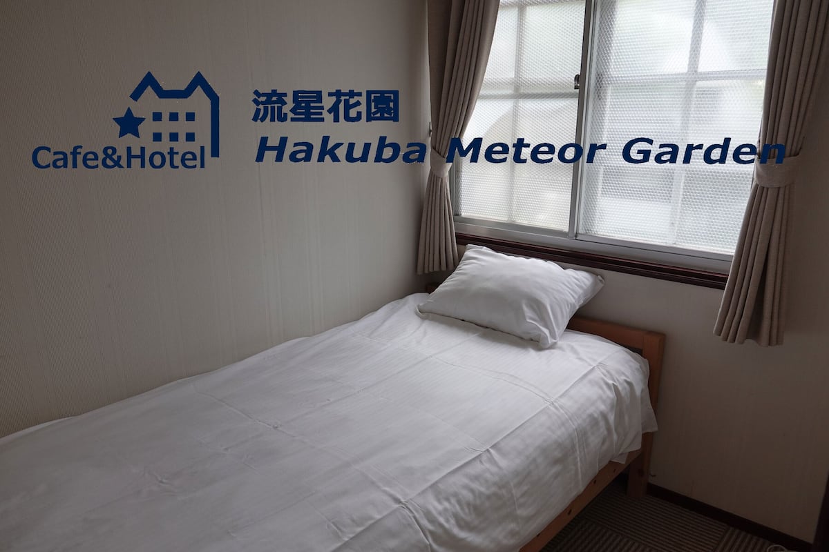 Ein Einzelbett mit weißer Bettwäsche in einem Hotelzimmer.