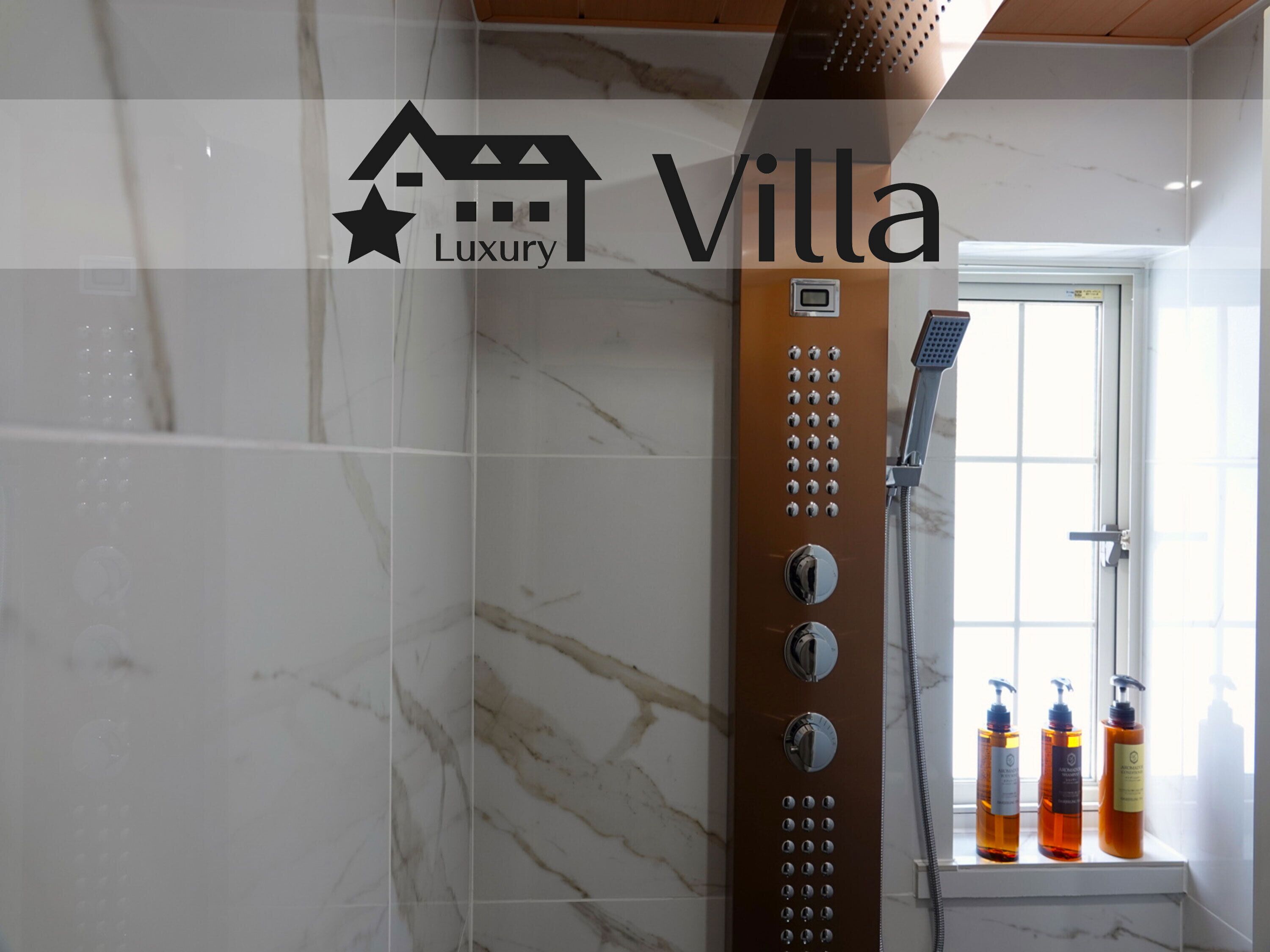 A bathroom with a shower, marble tiles, and three bottles of shampoo on a shelf.