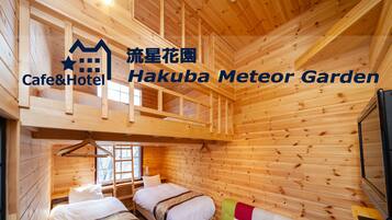 A wooden cabin with two beds, a bunk bed, and a colorful sofa.