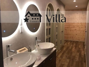 A modern bathroom with two large oval sinks, a mirror, and a wooden floor. - Meteor Garden (Hakuba)