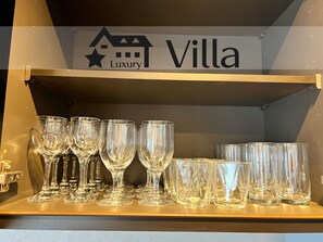 A shelf with various wine glasses and a sign above reading "Villa Luxury".