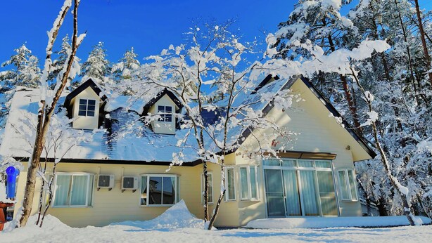 A two-story house with a snow-covered roof and trees. - Meteor Garden (Hakuba)
