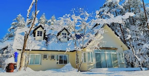 A two-story house with a snow-covered roof and trees. - Meteor Garden (Hakuba)