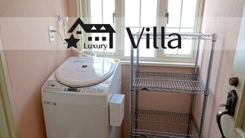 A compact laundry area with a washing machine, a metal shelf unit, and a window providing natural light.