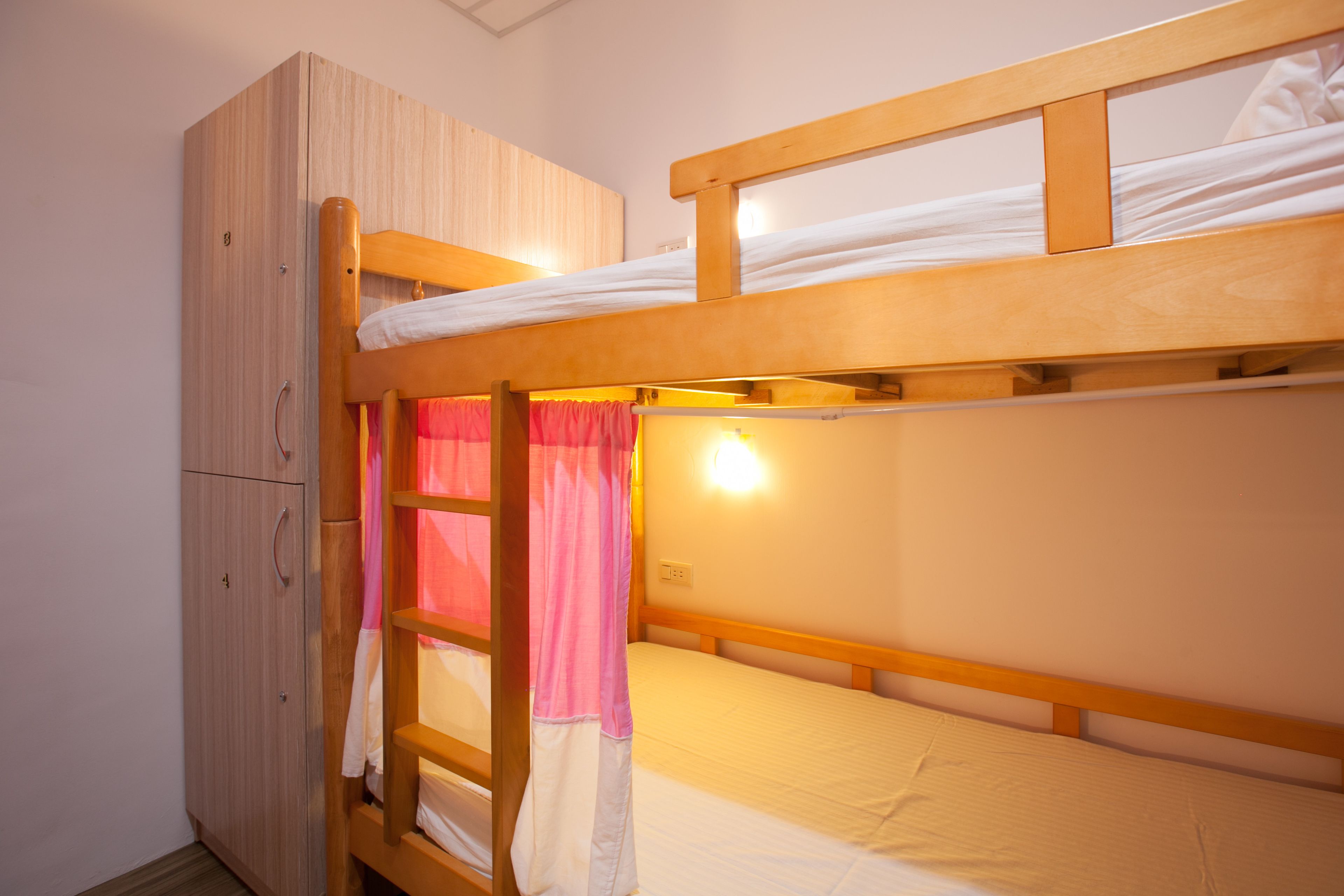 A bunk bed with a wooden headboard and a wardrobe with a mirror.