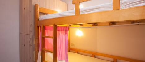 A bunk bed with a wooden headboard and a wardrobe with a mirror.