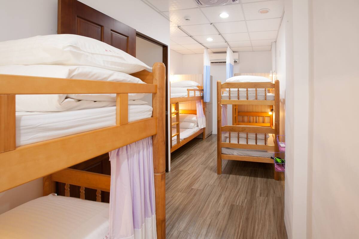 A room with bunk beds, wooden flooring, and a door.
