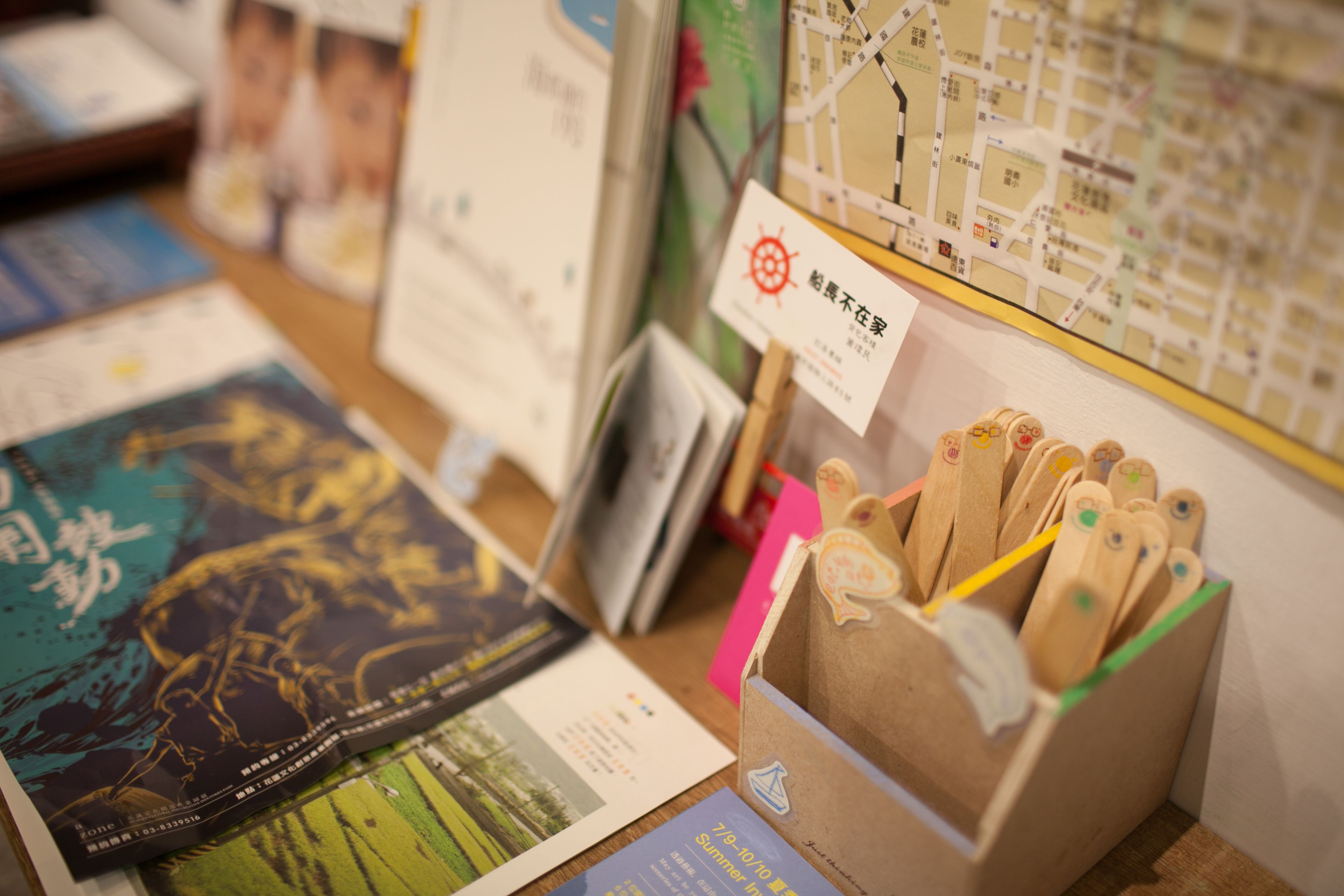 Une table sur laquelle sont disposés divers documents d’information, notamment des cartes et des brochures, ainsi qu’une boîte en bois contenant des crayons.