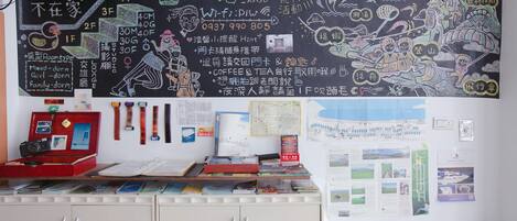 A room with a chalkboard wall displaying various information, a desk with a computer, and a cabinet with drawers.