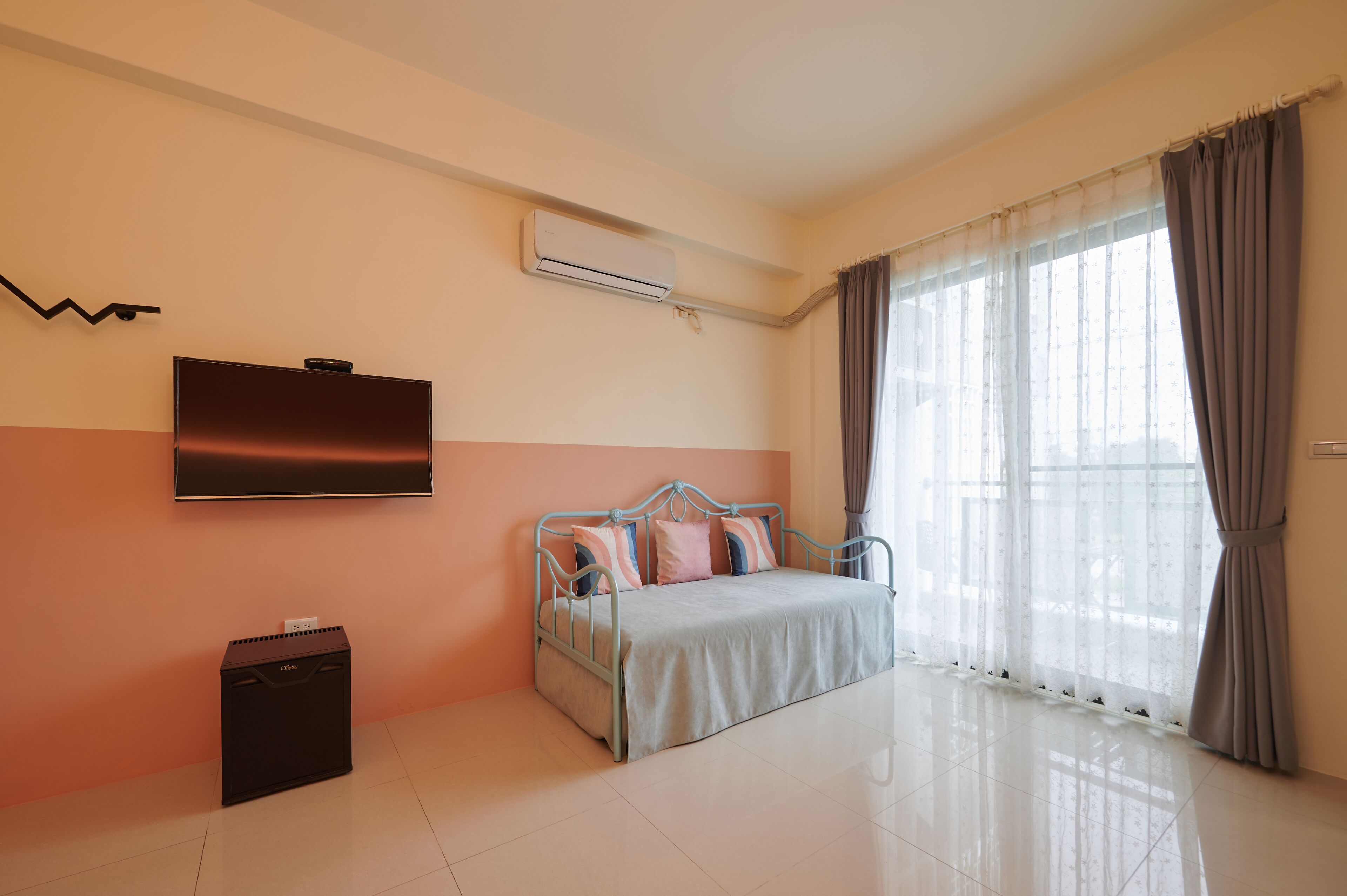 A bedroom with a bed, an air conditioner, a TV, and a suitcase.