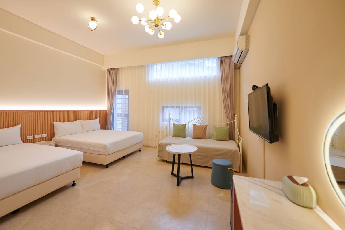 A hotel room with two beds, a small table, a TV, and a mirror.