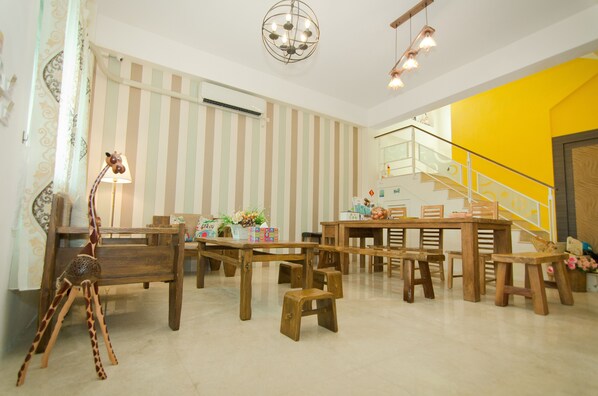A room with striped wallpaper, a wooden dining table, benches, a giraffe decoration, and a staircase with a yellow wall.