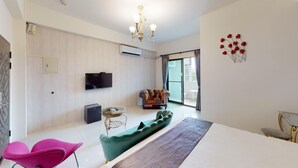 A modern hotel room with a flat-screen TV, a sofa, a dining table, and a large window with a view. - Avenue B&B (Hualien City)