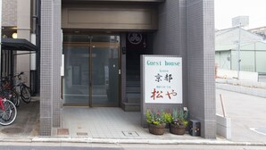 A two-story building with a sign reading "Guest House Kyoto Matsuo-ya".