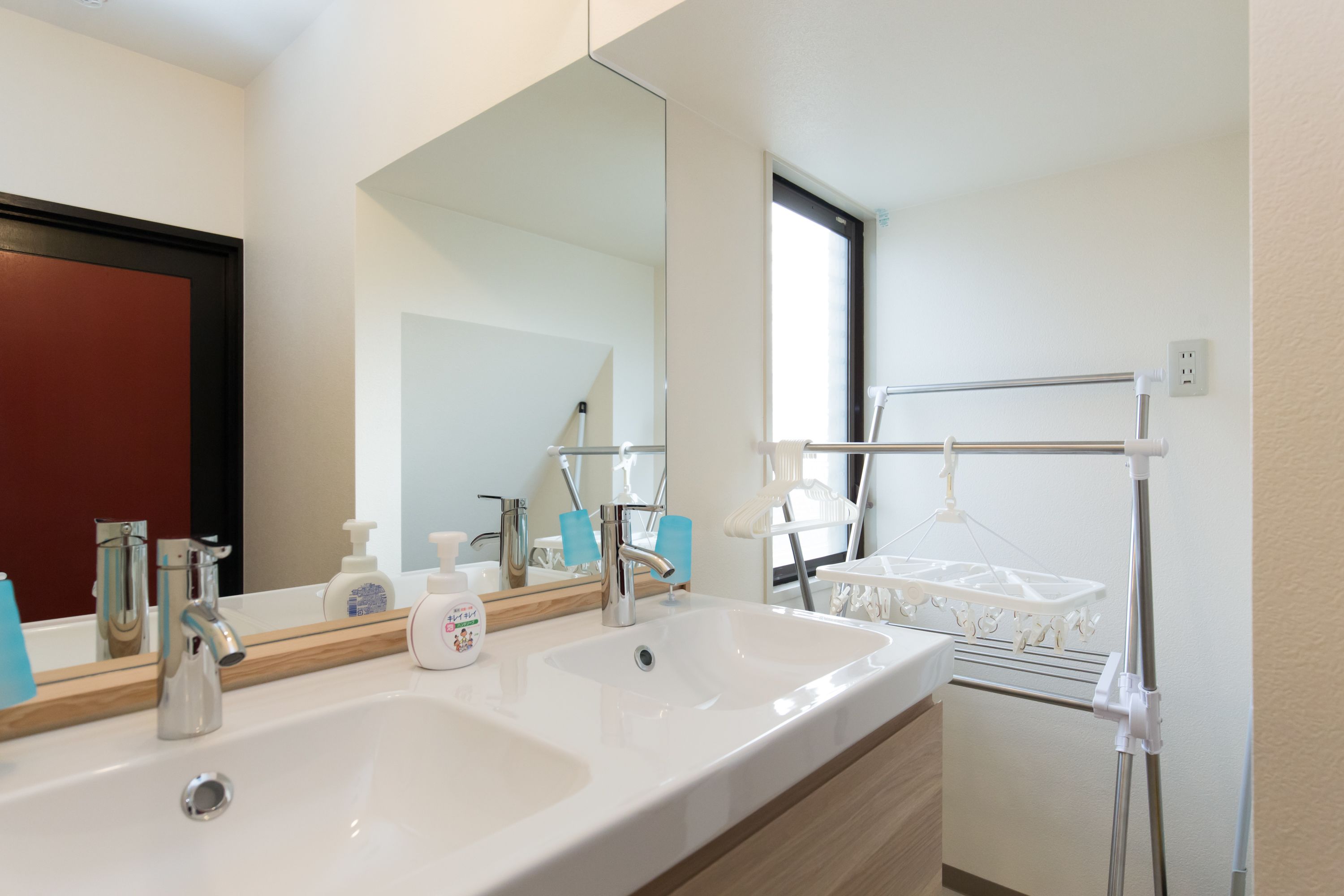 A modern bathroom with a large mirror, two sinks, and a towel rack.