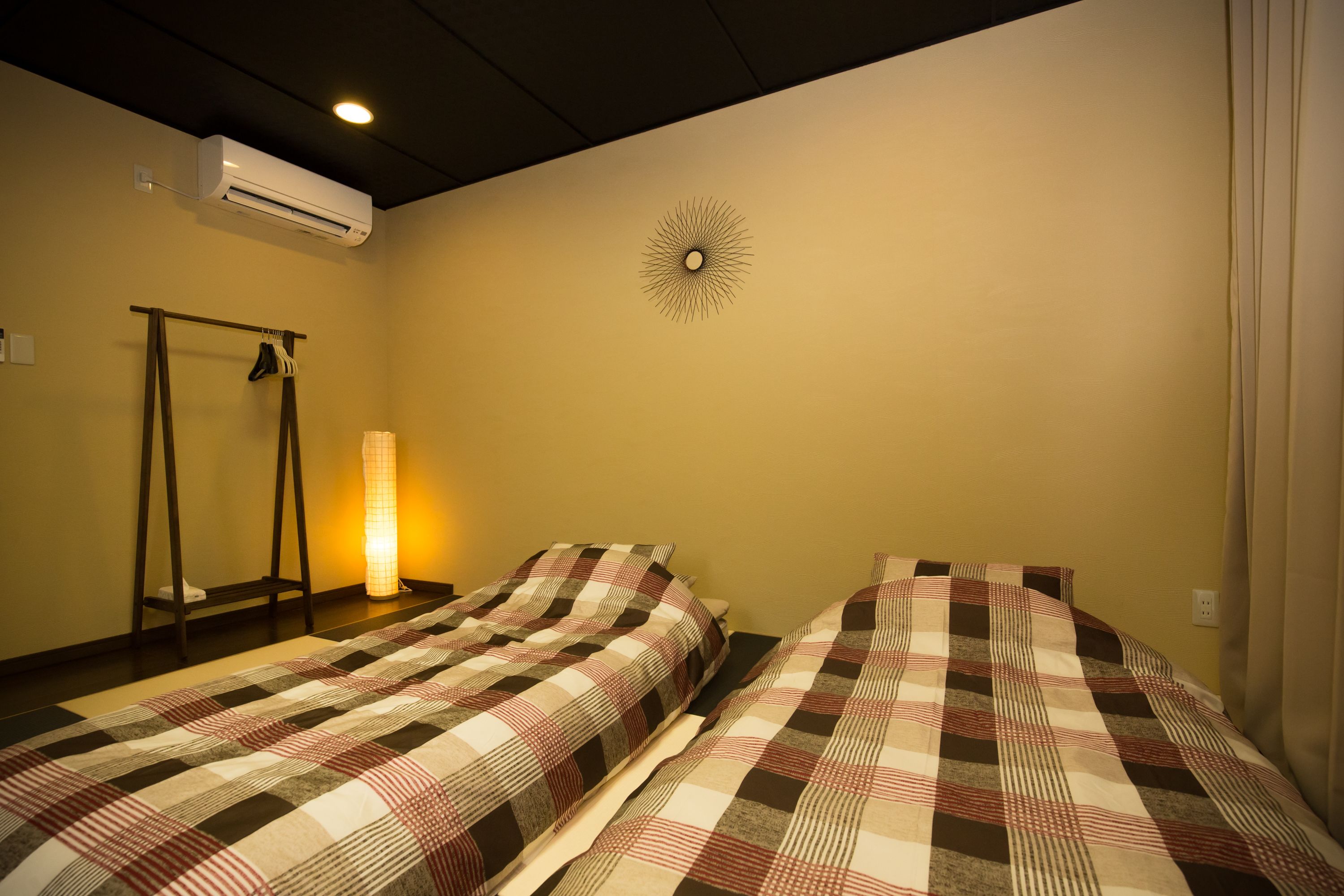 A room with two beds, a standing heater, and an air conditioner.
