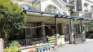 A building with a covered entrance, potted plants, and a sign indicating a business. - Greenpark Homestay (Luodong)