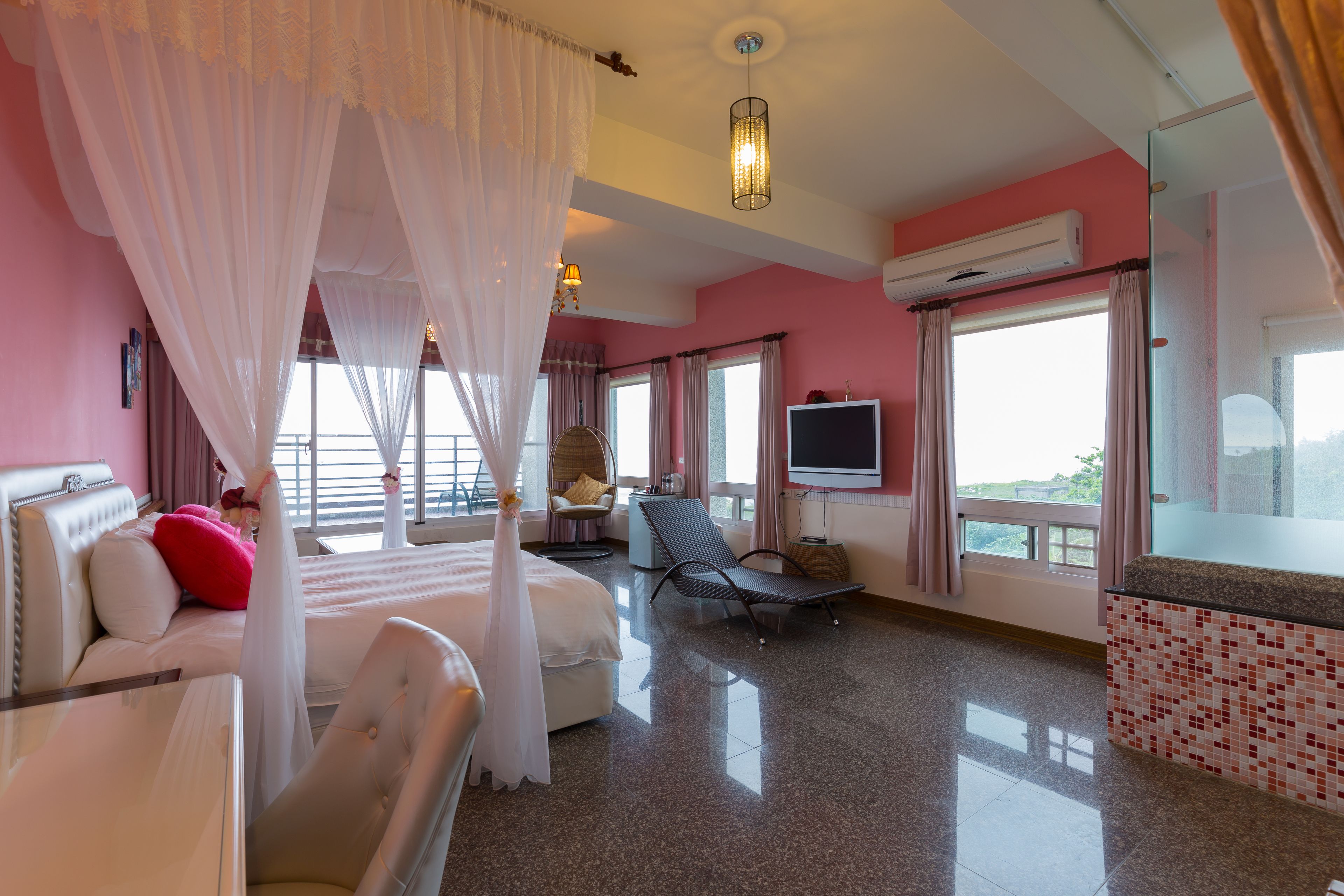 A hotel room with a bed, a chair, a TV, and a window with curtains.