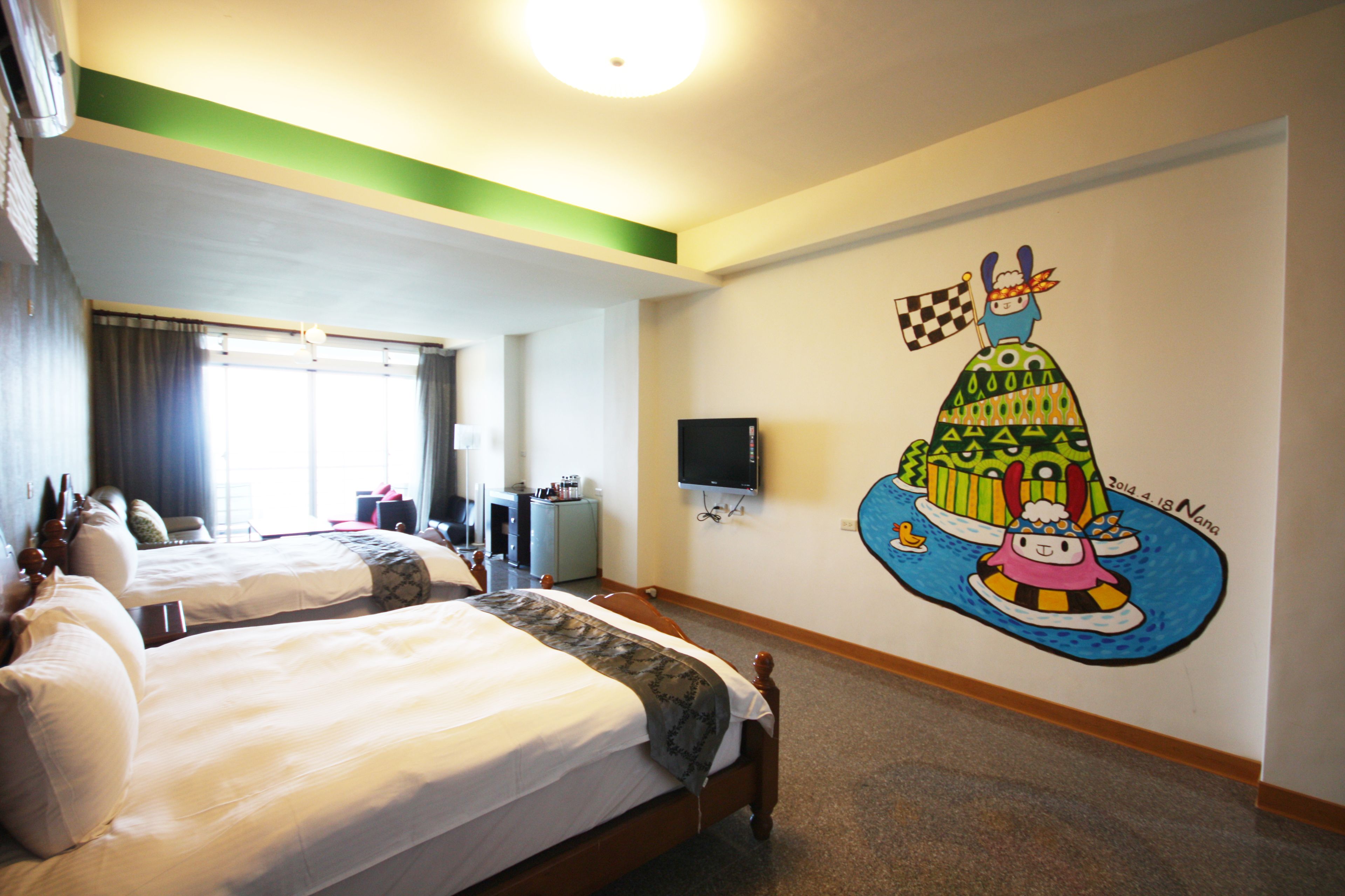 Quarto de hotel com duas camas, uma televisão e um mural na parede.