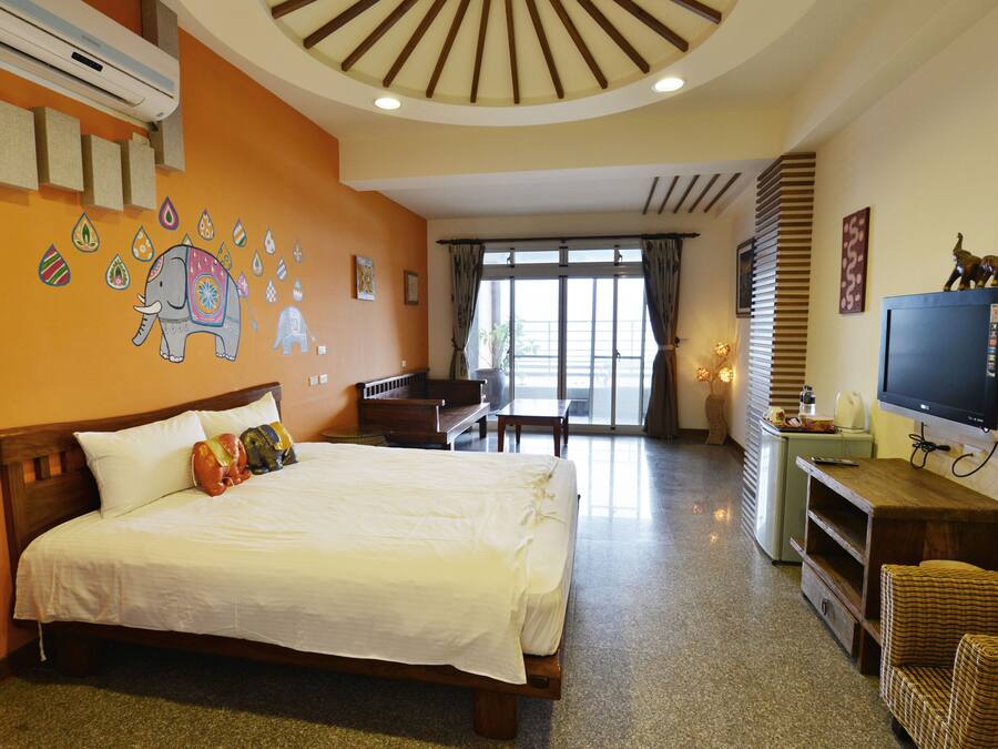 Habitació d'hotel amb llit, televisió, escriptori i balcó amb vistes.