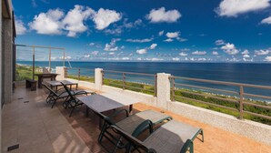 Un patio al aire libre con mesas y sillas, con vistas a la costa.