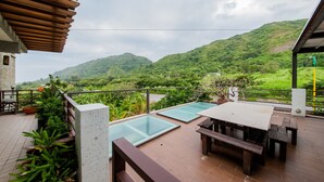 Una terraza con piscina, muebles de madera y plantas en macetas.