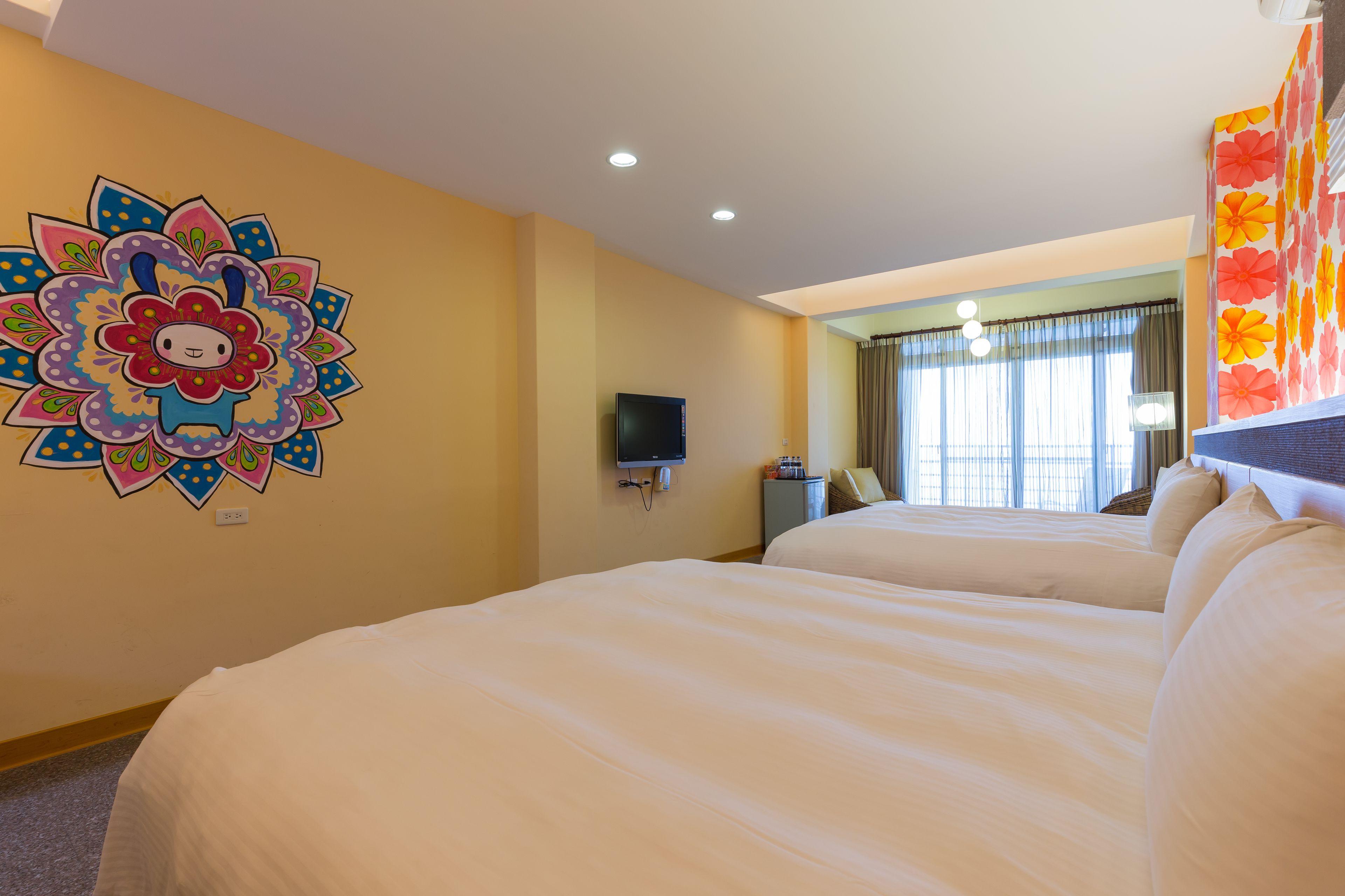 A hotel room with two beds, a TV, and a colorful wall decoration.