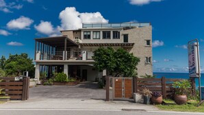 Un edificio moderno de dos pisos con balcón, ventanas amplias y vista al mar.