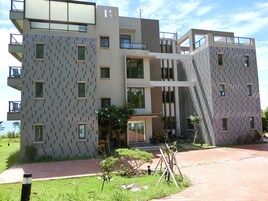 A modern multi-story building with a geometric facade, balconies, and large windows.