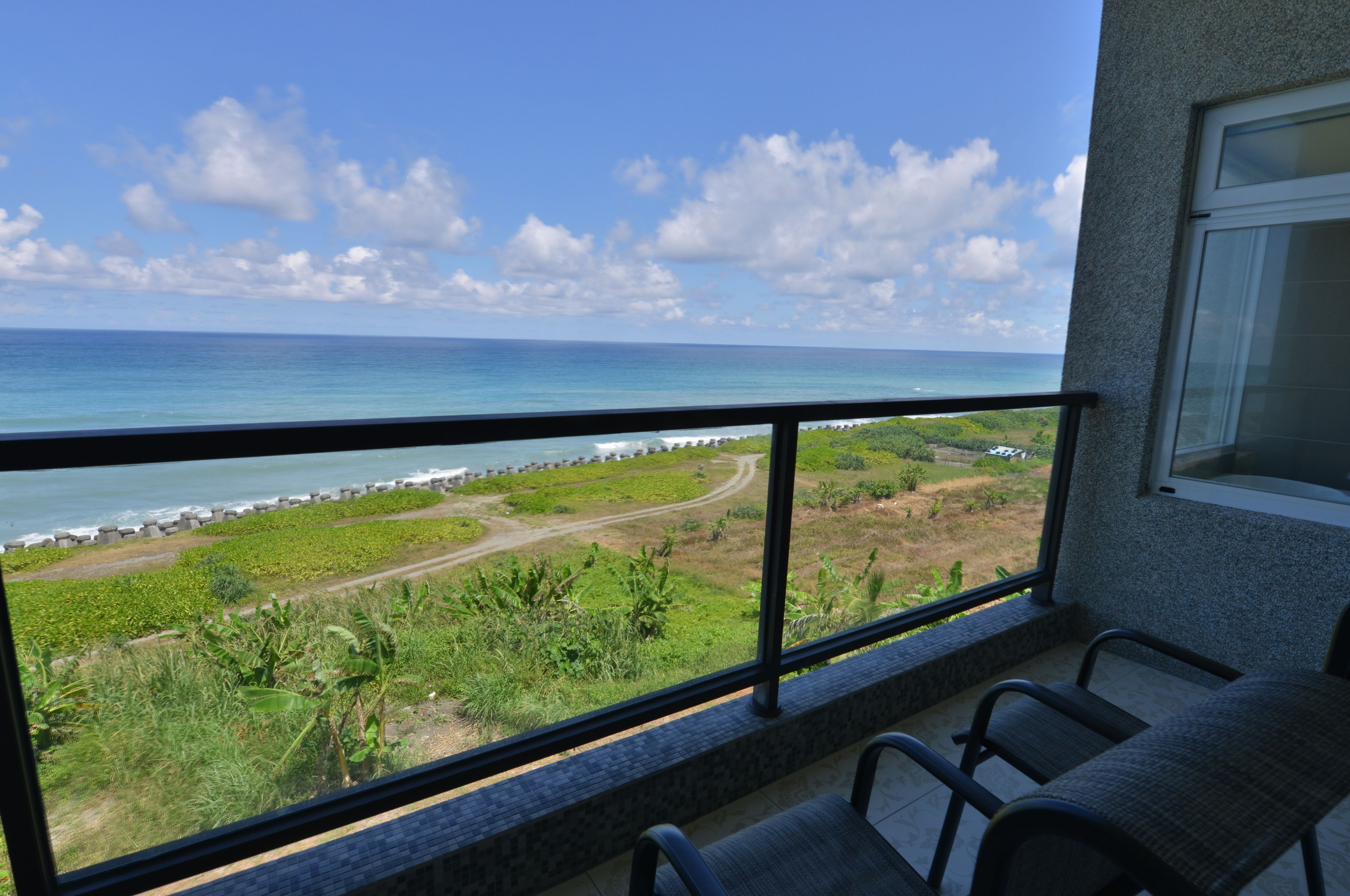 A balcony with a view of the ocean and a coastal path.