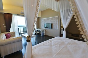 A bedroom with a four-poster bed, a sofa, a desk, and a television. - White Spray B&B (Shoufeng)