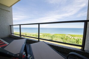 A balcony with a view of the ocean, a tiled floor, and two lounge chairs. - White Spray B&B (Shoufeng)