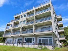 A multi-story building with balconies, large windows, and a flat roof.