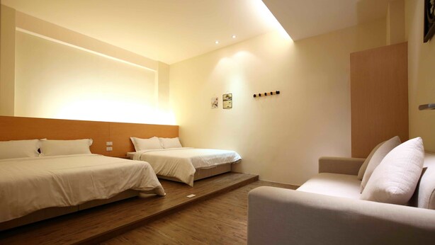 Quarto de hotel com uma cama grande, uma cama menor e um sofá.