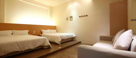 A hotel room with a large bed, a smaller bed, and a sofa.