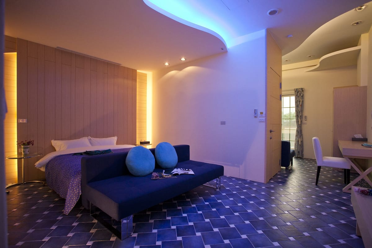 A modern bedroom with a bed, a blue sofa, and a small table.